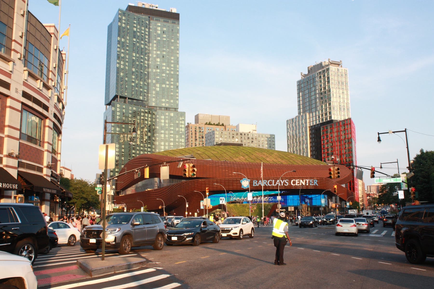 The weathered-steel oculus of the Barclays Center over Flatbush Avenue at golden hour